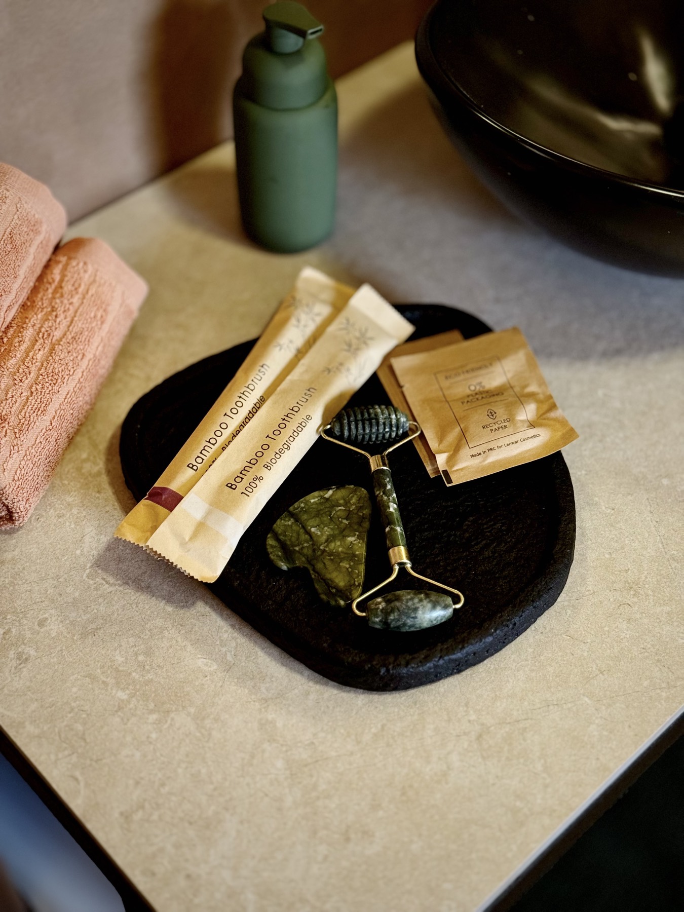 A jade gua sha and roller on a stone tray