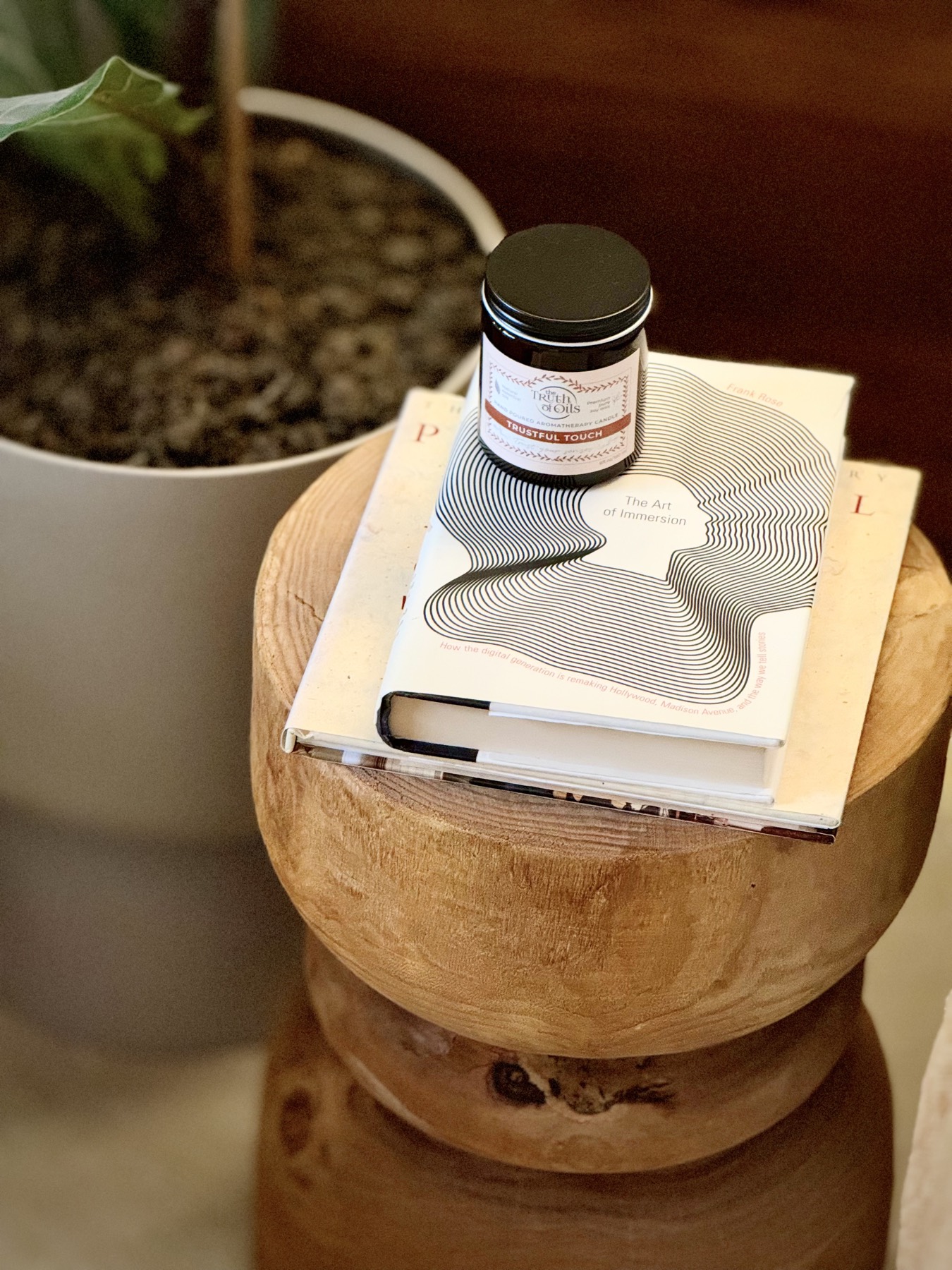 Books and a soy candle on a wooden stool